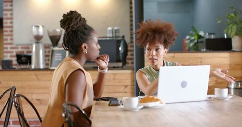 African american colleagues collaborating over laptop in coffeehouse discussing ideas and strategy
