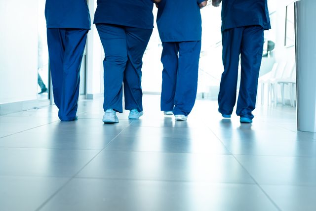 Low section of legs of female and male doctors wearing scrubs walking in hospital corridor - Download Free Stock Photos Pikwizard.com