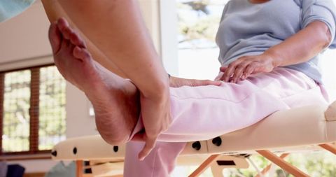 Senior woman undergoing rehabilitation with physiotherapist exercises