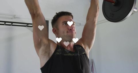 Determined athlete pressing barbell overhead in compact home garage gym with heart icons