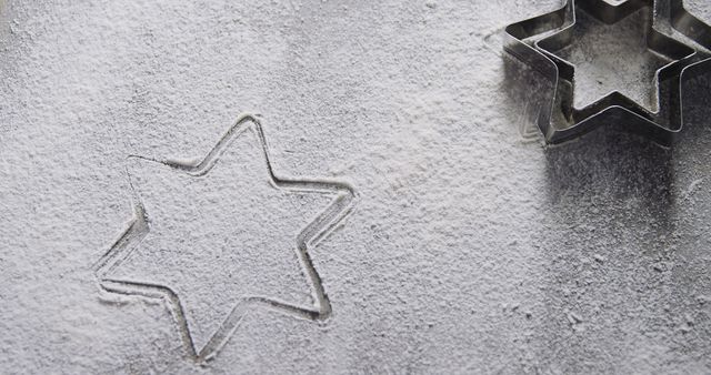 Image shows a star-shaped cookie cutter on a flour-dusted surface, often seen in holiday baking scenes. Useful for articles or advertisements related to baking, festive cookie ideas, holiday desserts, or kitchen tools. Ideal for use on cooking blogs, holiday recipe websites, or festive-themed print materials.