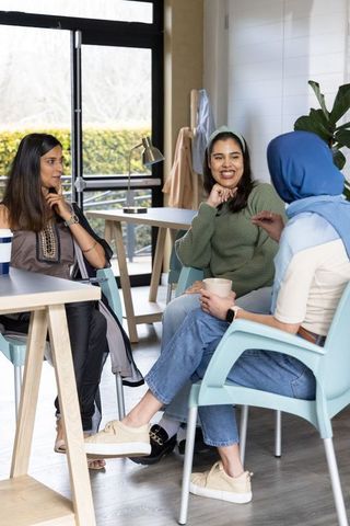 Multicultural women enjoying coffee and conversation in bright modern lounge, casual meetup