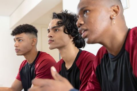 Focused diverse teenage teammates wearing maroon and black jerseys preparing for game