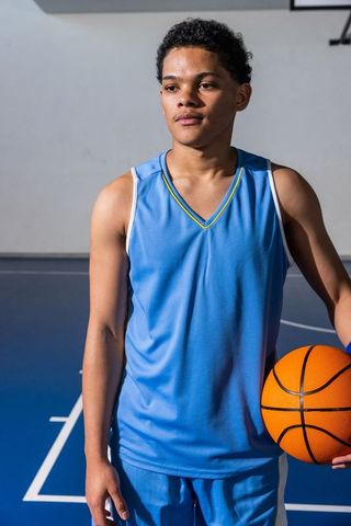 Teen basketball player holding ball on indoor court