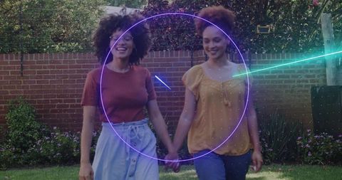 Walking friends holding hands in backyard smiling casual summer stroll with neon circle