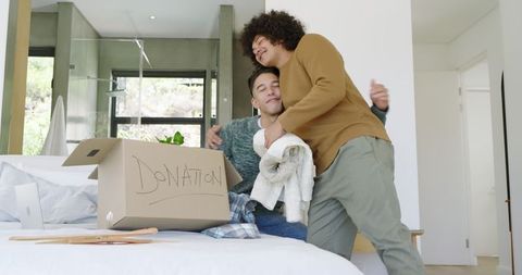 Couple Embracing While Sorting Charity Donation Box at Home