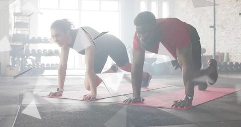 Man and woman holding plank on red mats during partner gym workout for core strength