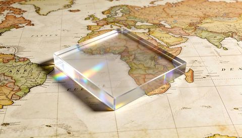 Acrylic prism revealing vintage world map with rainbow refraction and magnified grid