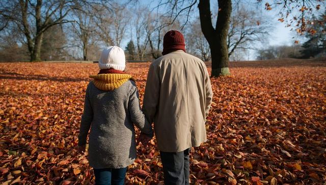 Senior couple holding hands walking through autumn leaves in park cozy fall romance