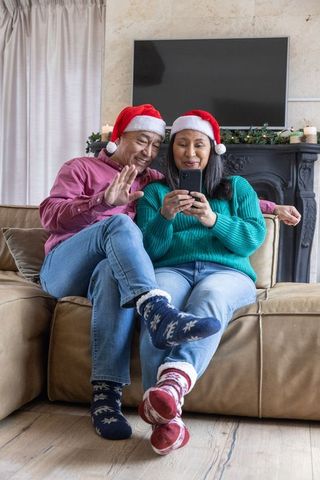 Senior Couple Celebrating Christmas with Smartphone on Cozy Sofa