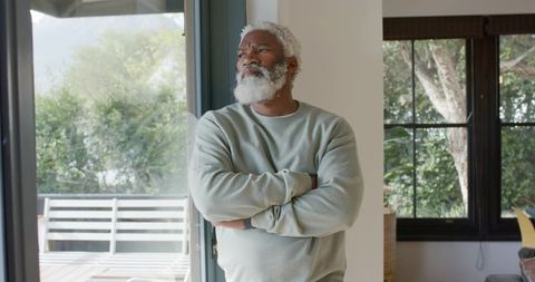 Senior man gazing peacefully through glass door in modern home