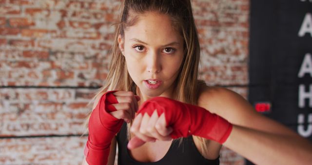 Young woman with boxing wraps training in gym, ideal for promoting fitness programs, sports apparel, and empowering women's athletic campaigns.