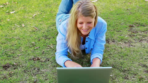 Joyful Woman Relaxing on Grass with Laptop in Park