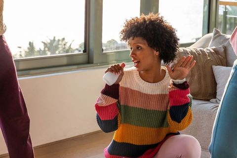 Young african american woman singing with wireless microphone in cozy sunlit living room
