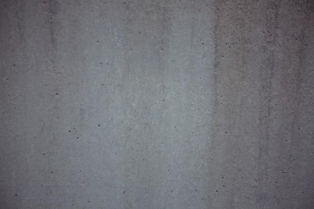 This image shows a close-up of a weathered concrete wall, highlighting its rough texture and aged appearance. Ideal for use in design projects requiring a grunge or industrial aesthetic, such as backgrounds for websites, posters, or presentations. It can also be used in architectural or construction-related content to depict raw materials or urban environments.