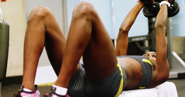 An African American woman engages in a workout routine, focusing on her abdominal muscles, with copy space. Her dedication to fitness and health is evident as she performs exercises in a gym setting.