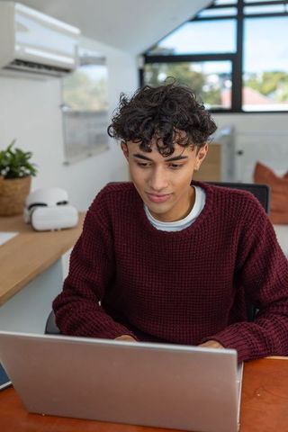 Young man working on laptop in cozy home office environment