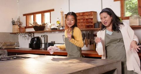 Mother and Daughter Joyfully Cleaning Together in Cozy Kitchen