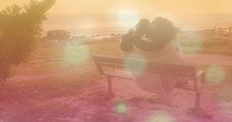 Romantic Couple on Bench Overlooking Ocean Sunset