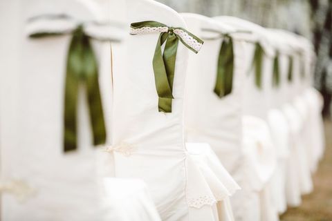 Elegant white covered marquee chairs with green ribbon ties bows photo