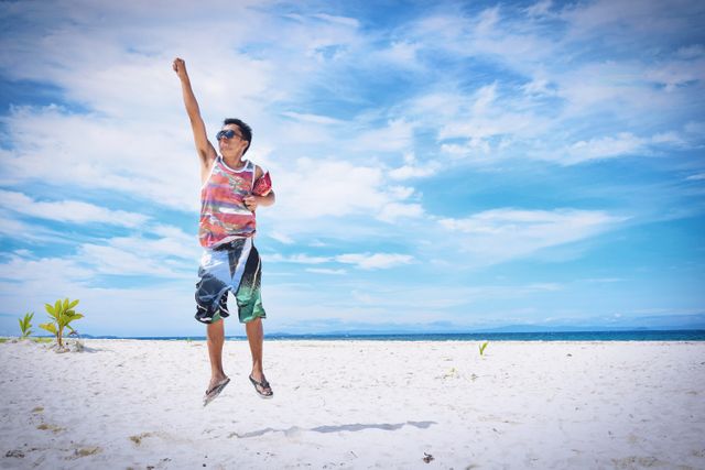 Joyful Young Man Jumping at Sandy Beach on Sunny Day - Download Free Stock Photos Pikwizard.com