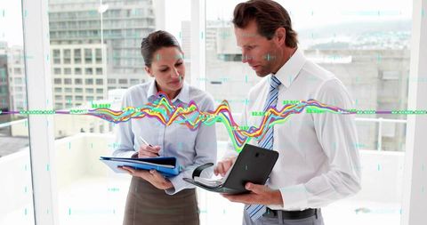 Executives reviewing financial analytics on tablet and clipboard with colorful data overlay
