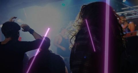 Dancing crowd with long curly hair under pink neon beams in nightclub haze