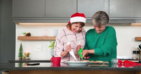 Mother and Daughter Decorating Holiday Cookies in Kitchen