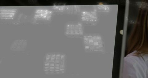 Monitor reflecting led grid, woman in white blouse standing in background