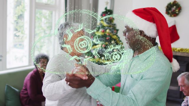 African American senior couple dancing joyfully at a festive Christmas gathering, with digital cloud graphics overlay. A colorful Christmas tree in the background adds to the holiday cheer. Suitable for themes highlighting technology in festive settings, family bonding during holidays, and joyful celebrations.