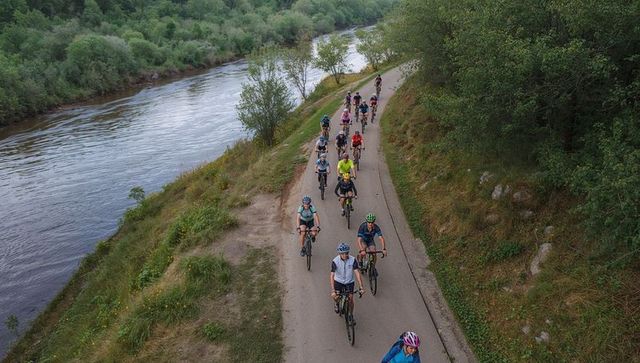 Cycling Group Riding Along Scenic Riverbank Trail