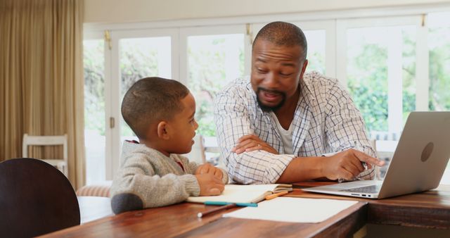 Father helping son with homework on laptop in living room - Download Free Stock Images Pikwizard.com