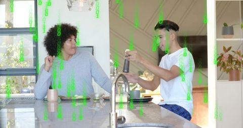 Young man grinding coffee at modern kitchen island while partner watching, green data overlay