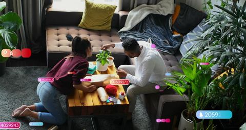 Couple Wrapping Gifts Amid Digital Social Media Alerts