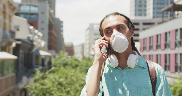 Young Man in Face Mask Talking on Phone Outdoors - Download Free Stock Images Pikwizard.com