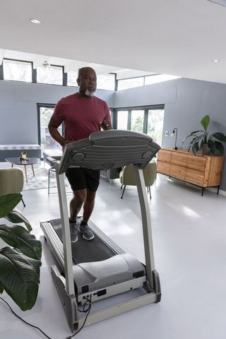 Elderly Man Jogging on Treadmill at Home Surrounded by Plants