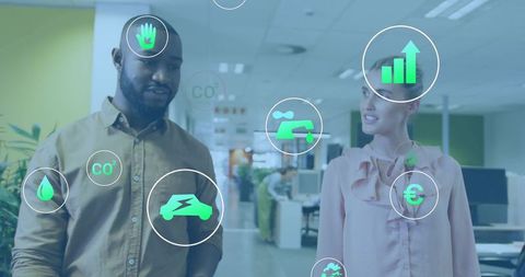 Walking colleagues discussing green tech icons in modern office promoting sustainability