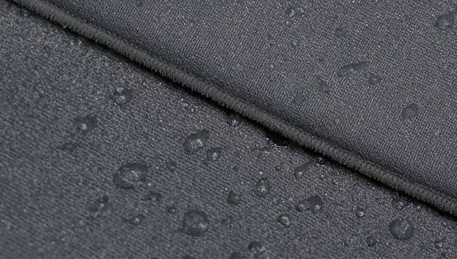 Macro close-up dark charcoal water-repellent textile with diagonal stitched seam detail
