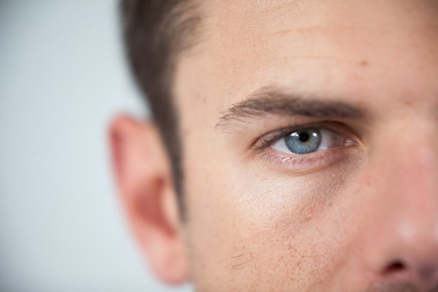 Close-up of a man's eye wearing a contact lens, showcasing the detail of the eye and skin. Useful for articles or advertisements related to vision care, contact lenses, optical health, and personal care products.