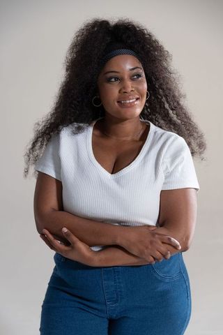 Confident african american woman standing with arms crossed wearing white top and denim