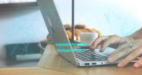 Typing hands on laptop with blue holographic network overlay and coffee