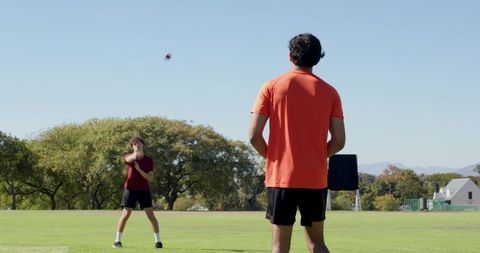 Athletes practicing catch drills on sunlit grass field during outdoor training session