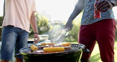 Diverse Friends Grilling Corn and Burgers in Backyard