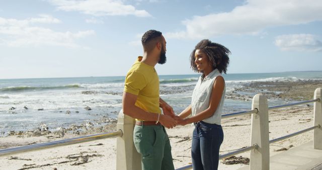 Romantic diverse couple standing, holding hands and smiling on sunny promenade, copy space. Summer, vacation, romance, love, relationship, free time and lifestyle, unaltered.