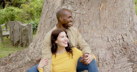 Happy Couple Embracing by Tree Trunk in Serene Park
