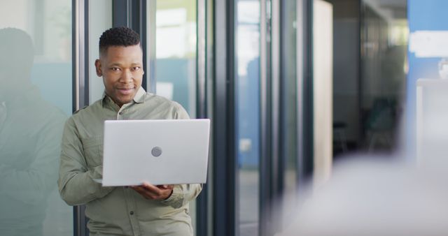 Confident Professional Holding Laptop in Modern Office Space - Download Free Stock Images Pikwizard.com