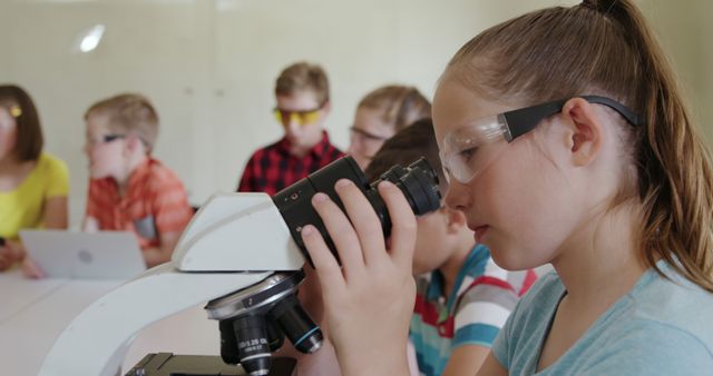 Group of young students engaged in a science experiment, using a microscope while wearing safety goggles. Ideal for illustrating educational materials, science workshops, promotional materials for schools, or articles about STEM education, childhood learning experiences, and classroom activities.