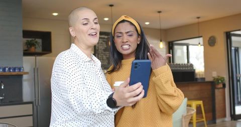 Multicultural friends taking selfie in cafe, sharing coffee and laughter, modern interior