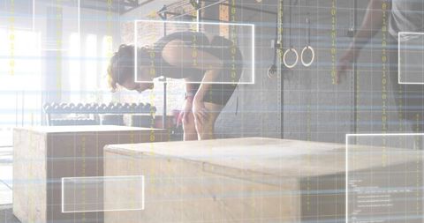 Woman pausing after intense plyo workout in industrial gym with daylight and dumbbells