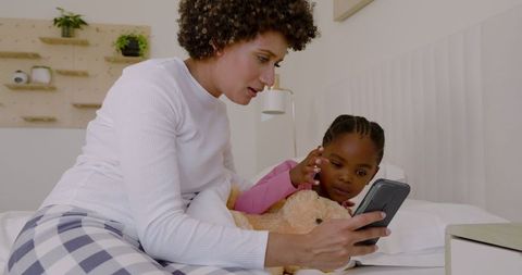 Mother and Daughter Bonding over Smartphone in Cozy Bedroom